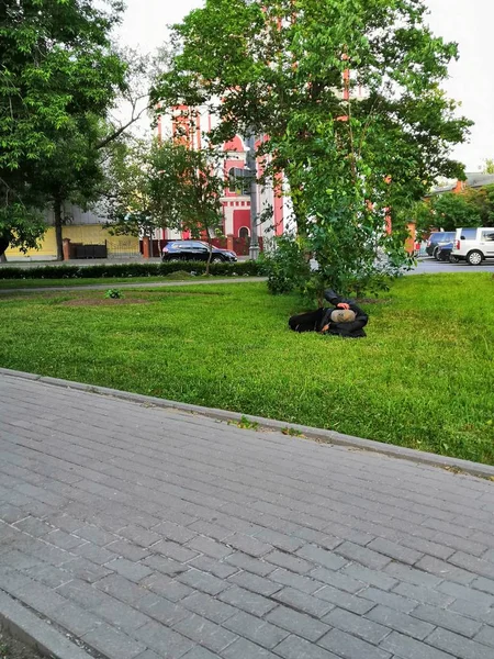 O trabalhador dorme debaixo da árvore no intervalo. sem-teto dormindo no gramado em um dia de verão . — Fotografia de Stock