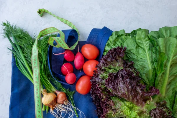 Gri arka planda taze sebzeler. Aromatik otlar, taze fitness sebzeleri salatalıklar ve domatesler, turplar ve soğanlar, salata..