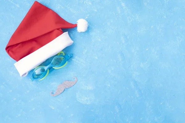 Yüzme ve bıyık için gözlüklerle Noel Baba 'nın şapkası. Yüzme Havuzu yakınındaki su, terlik ve havuz gözlükleri ile yılbaşı tatili, sandalet ve yüzme gözlükleri