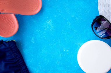 Yaz tatili konsepti, yaz seyahati aksesuarları açık mavi arka planda uzanan şapka, güneş kremi ve metin için fotokopi alanı olan telefon.