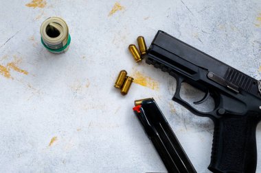 Çeşitli mezheplerden bir avuç Amerikan doları ve bir silah.
