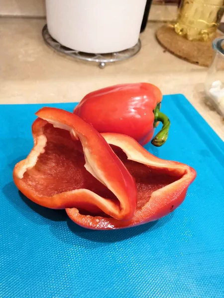 Červený sladký pepř se semínky. Řezání papriky ve tvaru tulipánového květu na modrém pozadí. Organické jídlo. Koncept zdravé stravy. — Stock fotografie