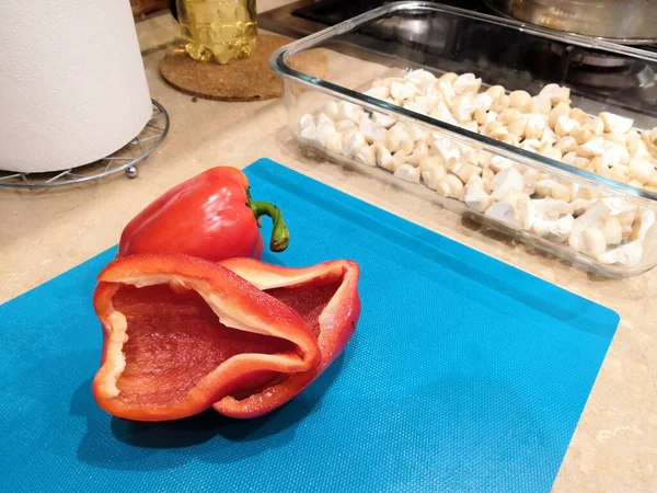 Červený sladký pepř se semínky. Řezání papriky ve tvaru tulipánového květu na modrém pozadí. Organické jídlo. Koncept zdravé stravy. — Stock fotografie