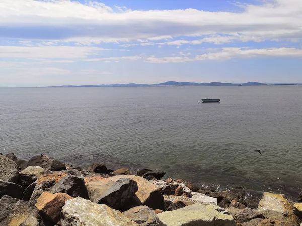 lonely boat in the sea sea shore with a stone embankment. beach in the cloudy day