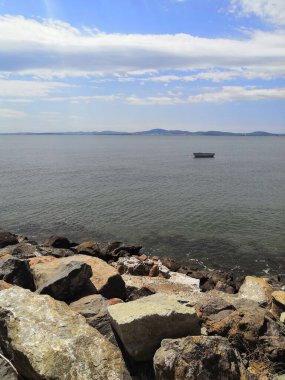 lonely boat in the sea sea shore with a stone embankment. beach in the cloudy day