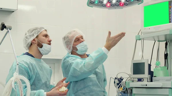 외과 의사는 모니터에 그의 손을 포인트합니다 — 스톡 사진