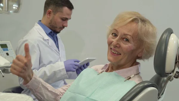 Жіночий клієнт показує великий палець на стоматологічному кріслі — стокове фото