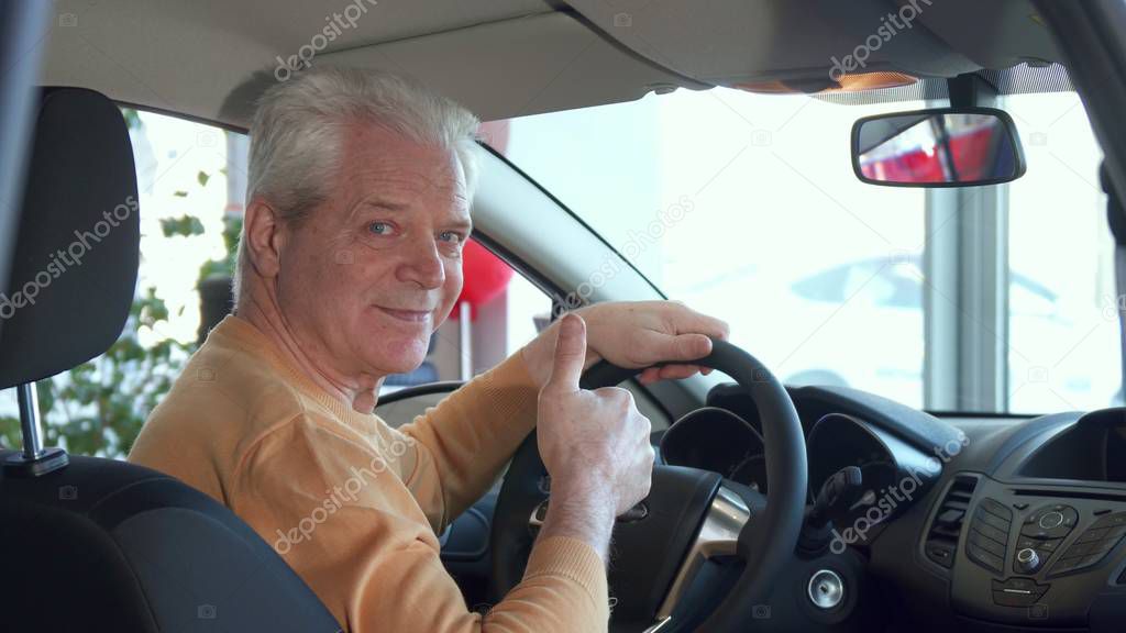 Senior man adjusts rear-view mirror inside the car