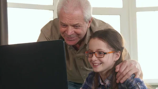 Menina e seu avô têm vídeo chat no laptop — Fotografia de Stock