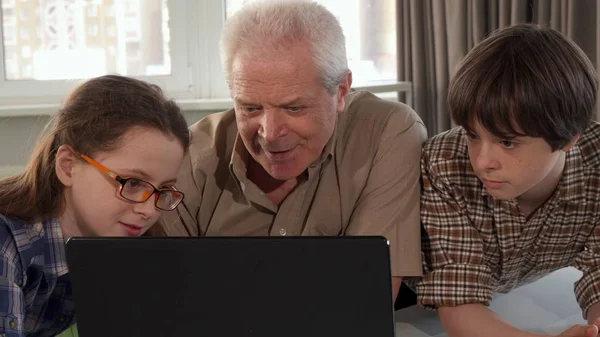 Девочка помогает дедушке печатать на ноутбуке — стоковое фото