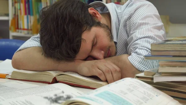 Männlicher Student wacht in der Bibliothek auf — Stockfoto