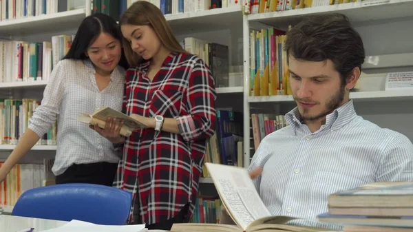 Студенты читают книгу в библиотеке — стоковое фото
