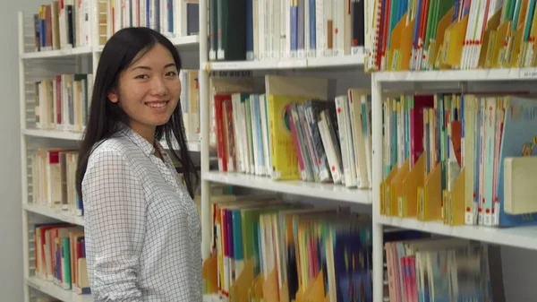 Girl puts academic journals on the rack at the library