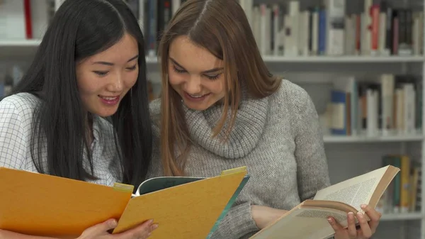 Studentin zeigt in der Bibliothek mit dem Zeigefinger ins Buch — Stockfoto