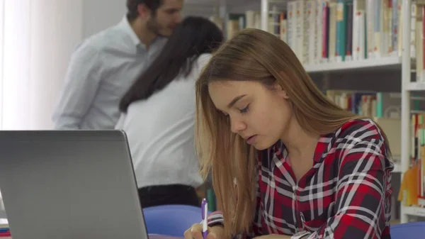 Dziewczyna zauważa z laptopa w bibliotece — Zdjęcie stockowe