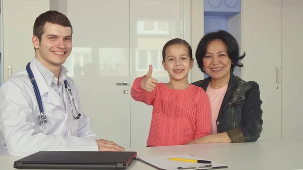 Маленькая девочка показывает большой палец рядом с доктором — стоковое фото