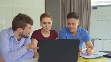 Genç insanlar bir şey ofiste dizüstü üzerinde tartışmak