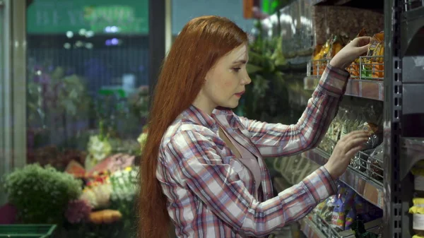 Girl chooses nuts at the hypermarket — Stock Photo, Image