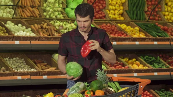 Человек кладет разные овощи в корзину — стоковое фото