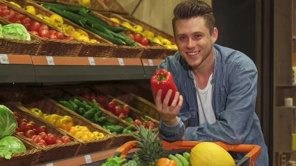 Мужчина осматривает перец в супермаркете — стоковое фото