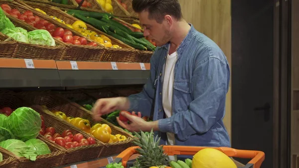 Парень покупает фрукты и овощи в гипермаркете — стоковое фото