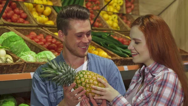 Пара нюхает ананас в гипермаркете. — стоковое фото