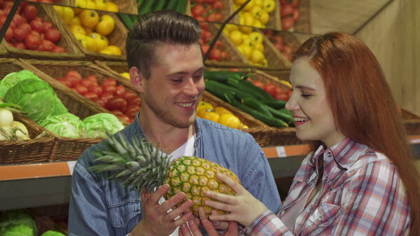 Couple smells the pineapple at the hypermarket