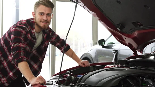 Симпатичный мужчина, осматривающий двигатель машины в салоне автосалона. — стоковое фото