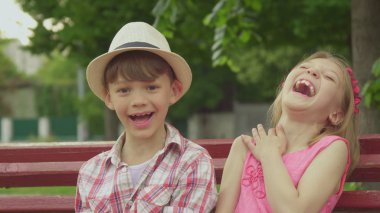 Küçük kız bankta çocuğa bir şey söylüyor