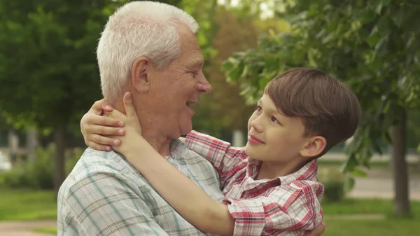 Little boy holds his hands behind his grandpas neck — Stock Photo, Image