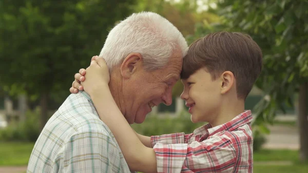 Старший мужчина и его внук прислонились лбами друг к другу — стоковое фото