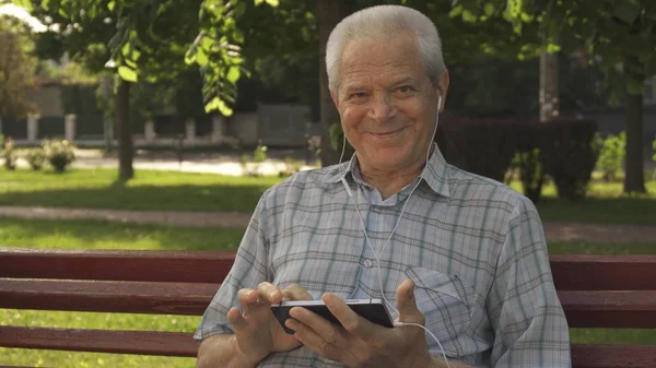 Hombre mayor utiliza tableta en el banco — Foto de Stock