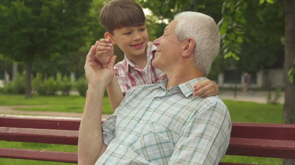 Little boy shuts grandpas eyes with his hands — Stock Photo, Image