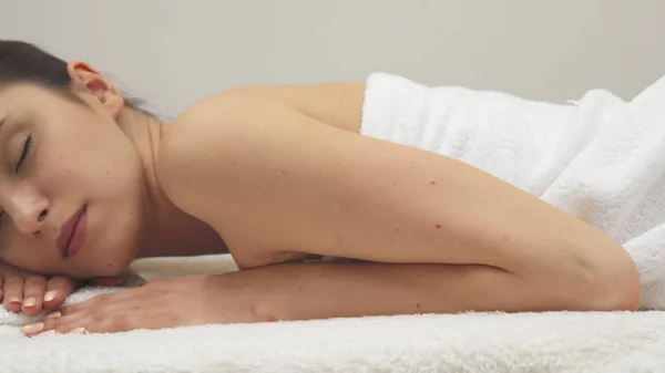 Menina encontra-se em seu estômago na mesa de massagem — Fotografia de Stock