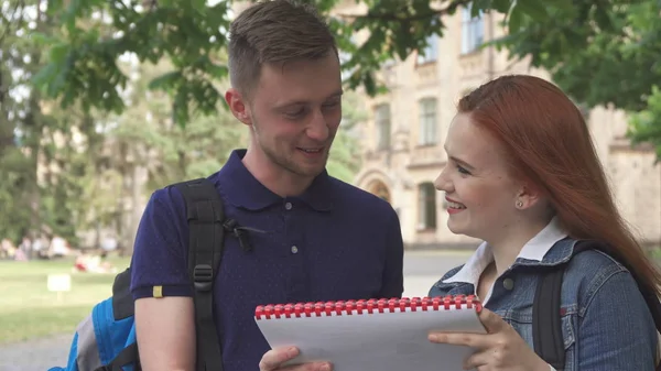 Kobiet student pyta jej kolega o czymś w notesie na kampusie — Zdjęcie stockowe