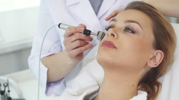 Kosmetikerin benutzt Iontophorese-Rolle für das Gesicht ihrer Klienten — Stockfoto