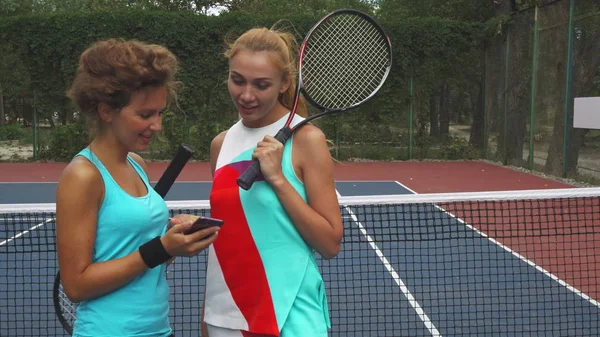 Zwei Tennismädchen diskutieren während sie ein Smartphone teilen — Stockfoto
