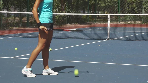 Beine von Frau schlagen Tennisschläger auf Ball neben Netz auf dem Platz — Stockfoto