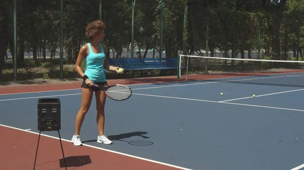 Krullend vrouw tennisballen te raken — Stockfoto