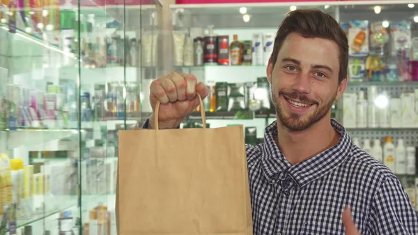 Homem mostrando um pacote com mercadorias na farmácia — Fotografia de Stock