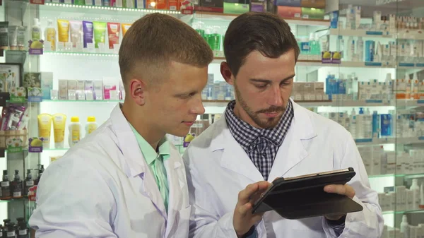 Dois farmacêuticos usando um tablet no trabalho — Fotografia de Stock