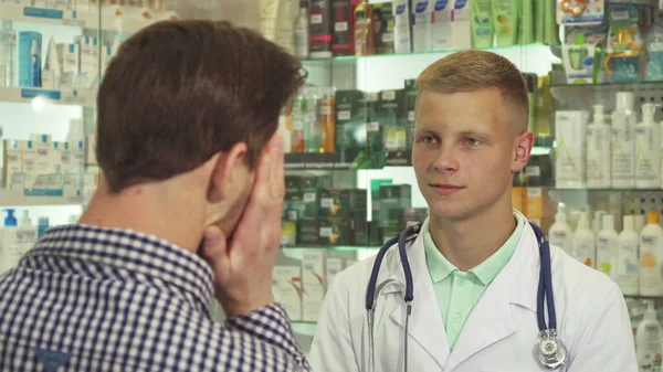 Врач разговаривает с пациентом с головной болью в аптеке — стоковое фото