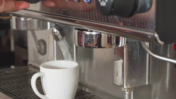 The coffee machine adds boiling water into the cup