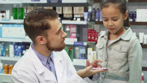 Bom farmacêutico dá um remédio menina — Fotografia de Stock