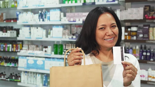 Uma mulher feliz tem um saco de compras e um cartão de crédito — Fotografia de Stock