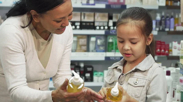 Una ragazza con sua figlia sceglie tubi di cosmetici in una farmacia — Foto Stock