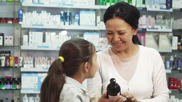 Uma mulher sorrindo escolhe com sua filha algo na farmácia — Fotografia de Stock