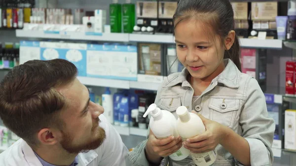 Lovely apothecary helps a young girl to choose what to buy — Stock Photo, Image