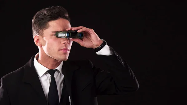 A business guy is trying to see something in the distance through binoculars — Stock Photo, Image