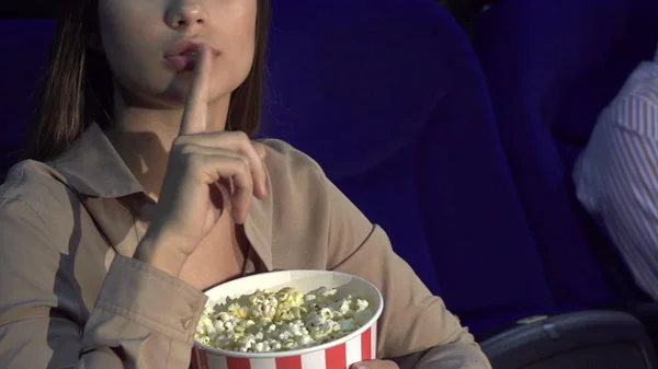 A close-up of how a girl eats popcorn and shows a sign of silence — Stock Photo, Image